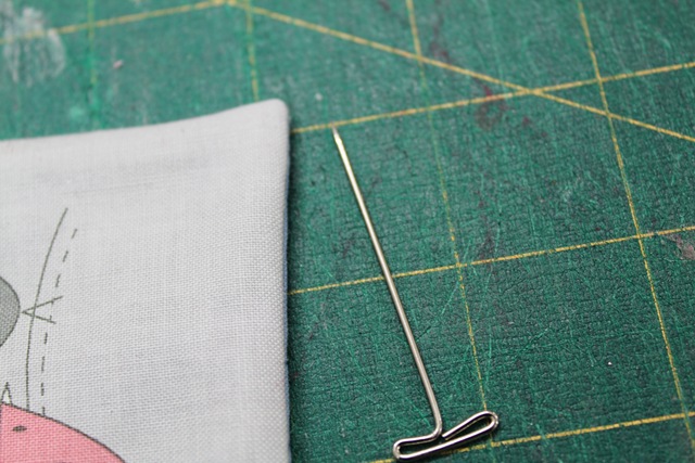 close up shot of a well-pressed piece of fabric and a pin - from A Quick and Simple Needlebook Tutorial by Helen of Hugs 'n Kisses