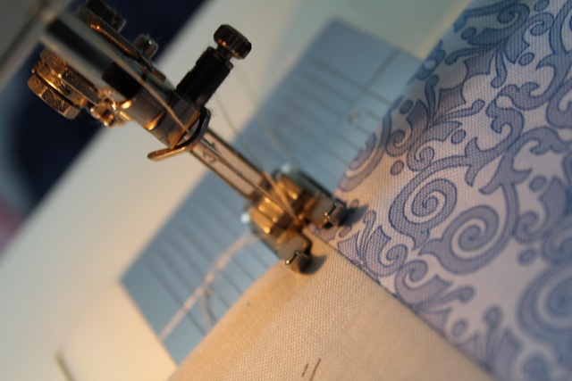a piece of fabric under a sewing machine needle - from A Quick and Simple Needlebook Tutorial by Helen of Hugs 'n Kisses